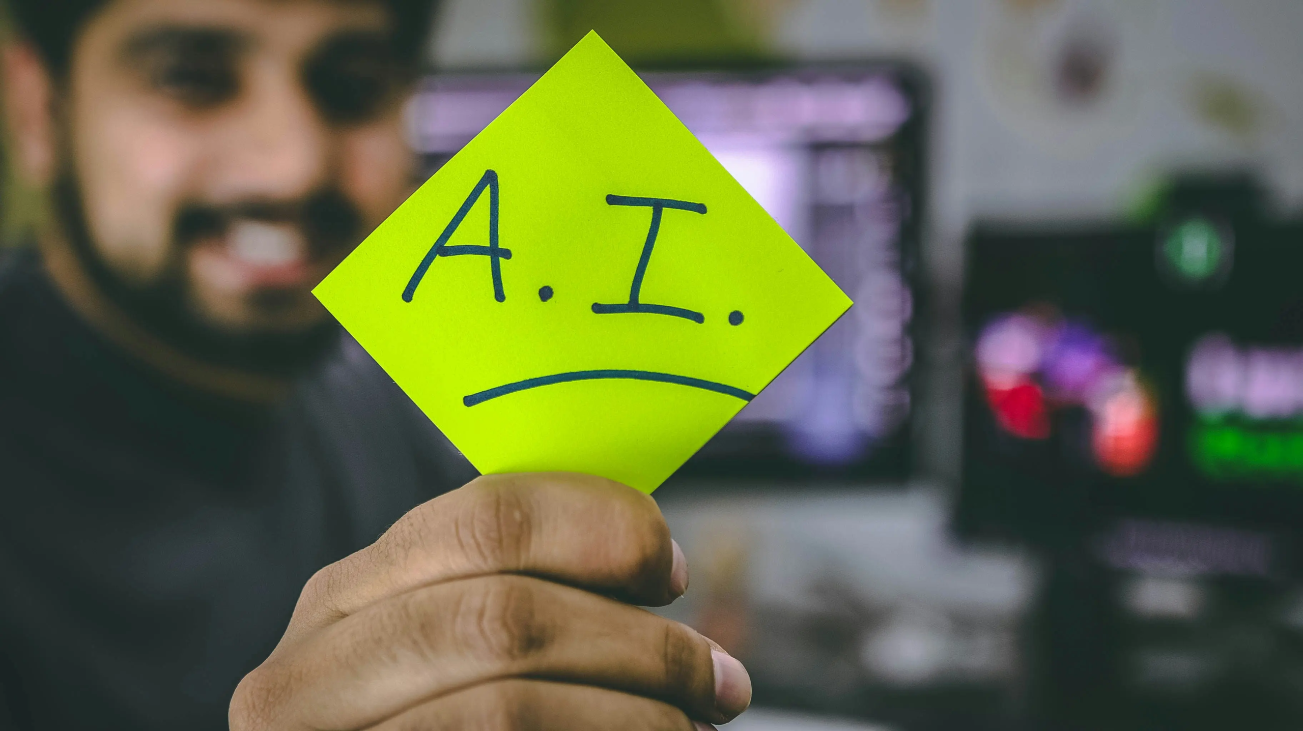A person holding a green paper with “AI” written on it.